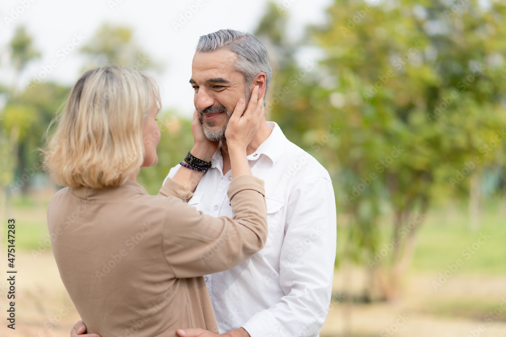Happy couple seniors in love wife touching her husband face and looking at each other while walking in the park.Retirement lifestyle concept Happy couple seniors in love wife touching her husband face and looking at each other while walking in the park.Retirement lifestyle concept
