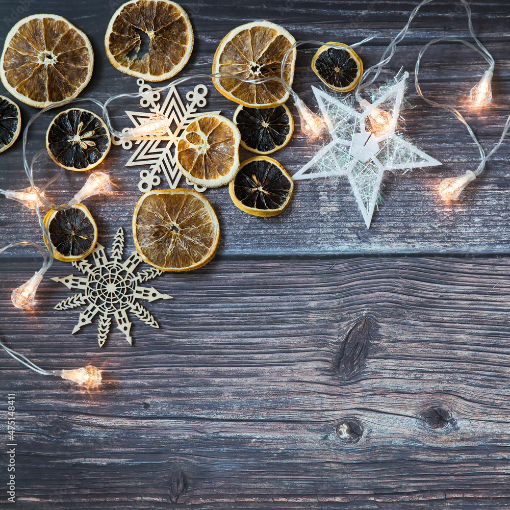 Dried orange slices, thread stars, cut snowflakes, garland on a wooden table. Place for your text. Shooting from above. Copy space Dried orange slices, thread stars, cut snowflakes, garland on a wooden table. Place for your text. Shooting from above. Copy space