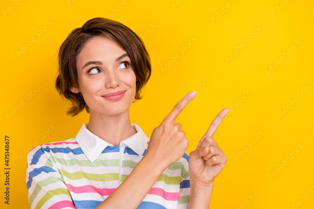 Photo of funny young brunette lady point look empty space wear sriped t-shirt isolated on yellow color background Photo of funny young brunette lady point look empty space wear sriped t-shirt isolated on yellow color background