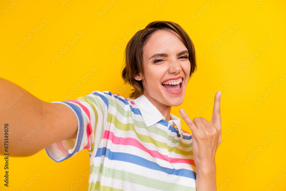Photo of funny young brunette lady do selfie show rock wear white t-shirt isolated on yellow color background Photo of funny young brunette lady do selfie show rock wear white t-shirt isolated on yellow color background