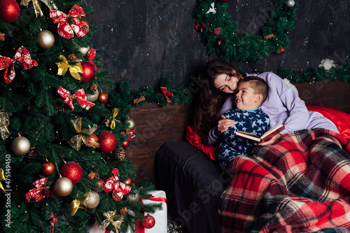 mother and son in the bedroom on the bed by the Christmas tree with gifts new year © dmitriisimakov