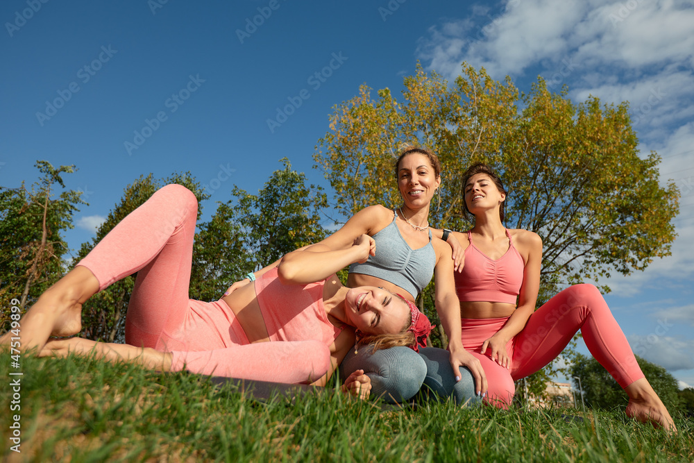 Smiling fitness women in training wear talking to each other standing on a street. Three women joggers standing on a street during their morning jog Smiling fitness women in training wear talking to each other standing on a street. Three women joggers standing on a street during their morning jog
