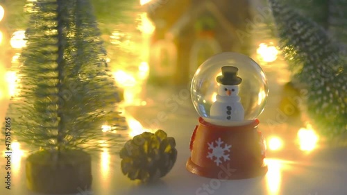 Snowman in globe with pine tree and shiny christmas lights with misty background