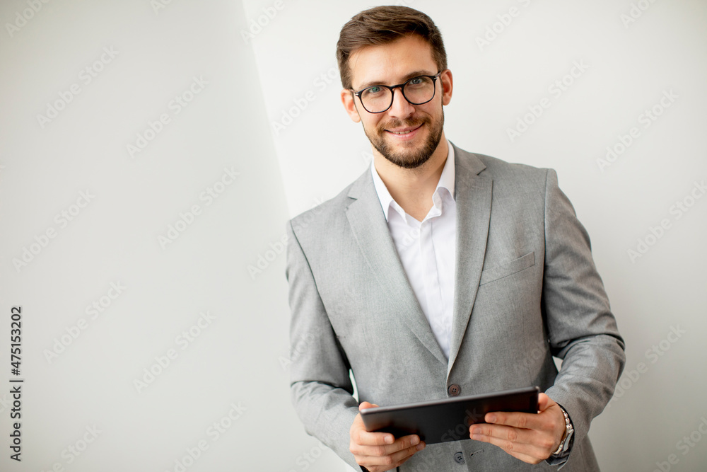Young modern businessman using digital tablet by the wall in the office Young modern businessman using digital tablet by the wall in the office