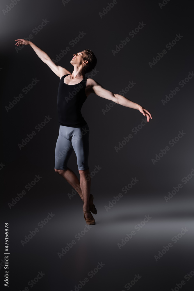 elegant man gesturing while performing ballet dance on black
