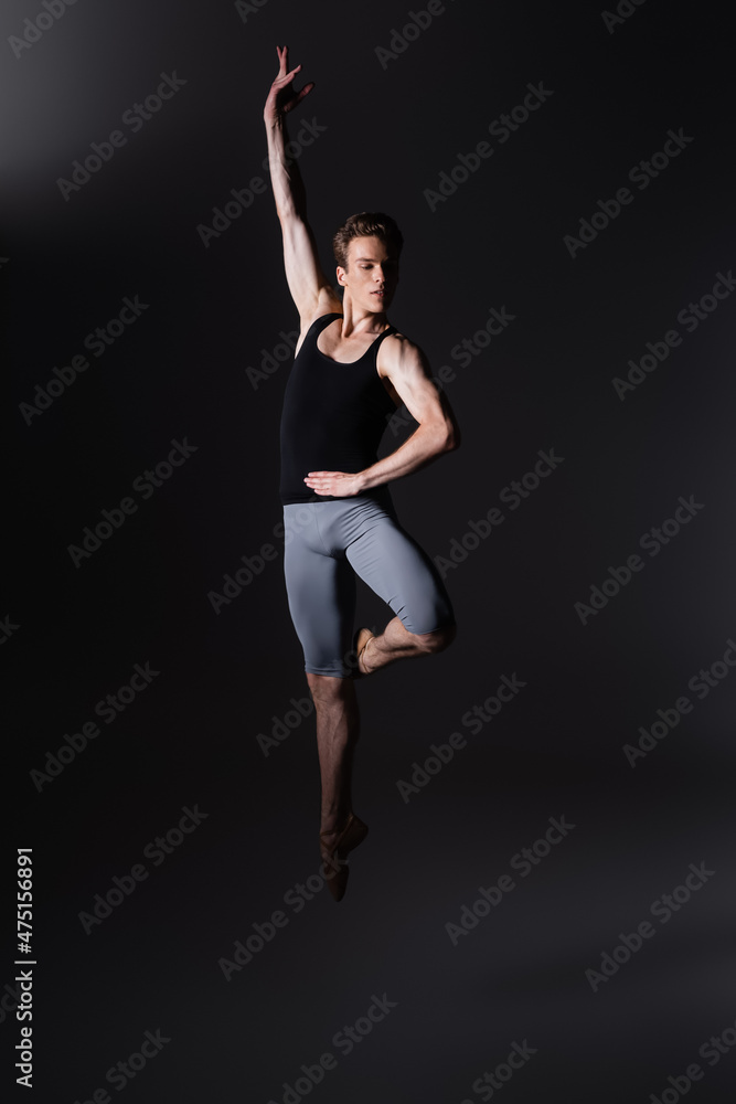 young and graceful dancer gesturing while performing ballet dance while jumping on black young and graceful dancer gesturing while performing ballet dance while jumping on black