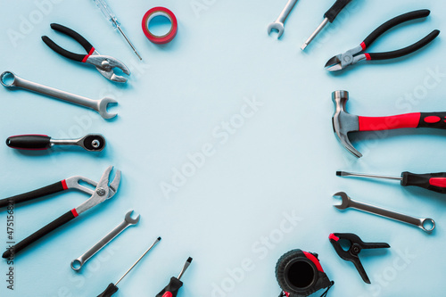 Working tools hammer, screwdriver, pliers, spanner and meter on light blue background. Top view, flat lay, copy space