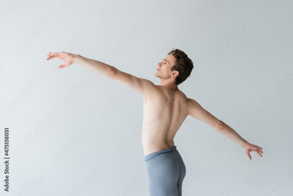 shirtless young man with outstretched hands performing ballet dance isolated on grey shirtless young man with outstretched hands performing ballet dance isolated on grey