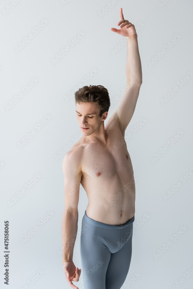 graceful and shirtless dancer with outstretched hand performing ballet dance isolated on gray