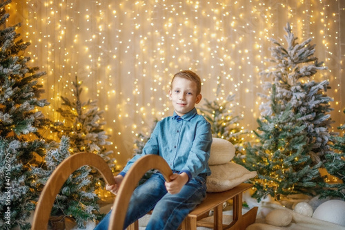 A child on a sled among the trees in the New Year's decorations.