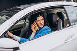 Woman sitting in car and using mobile phone