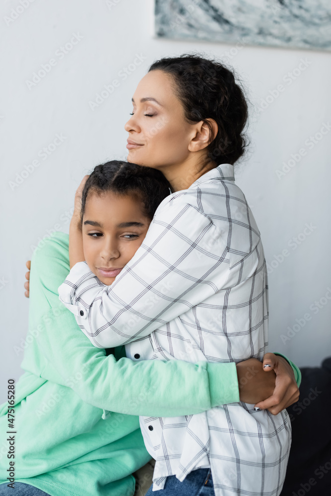 african american woman with closed eyes embracing frustrated daughter at home african american woman with closed eyes embracing frustrated daughter at home
