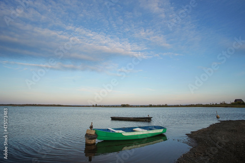               Two boats on the lake are moored near the shore  and there are small ripples on the surface of the water.