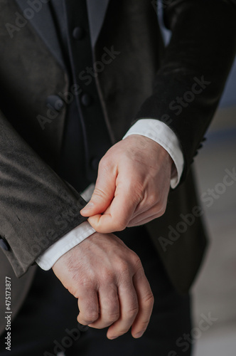 groom straightens the sleeve of his jacket, wedding suit