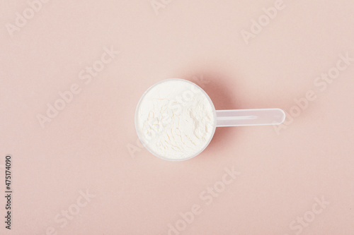 Fotografie Measuring spoon with protein powder on beige background