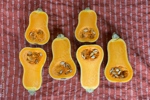 Honeynut butternut squash cut in half laying on a rust orange towel; prepping squash for cleaning and cooking