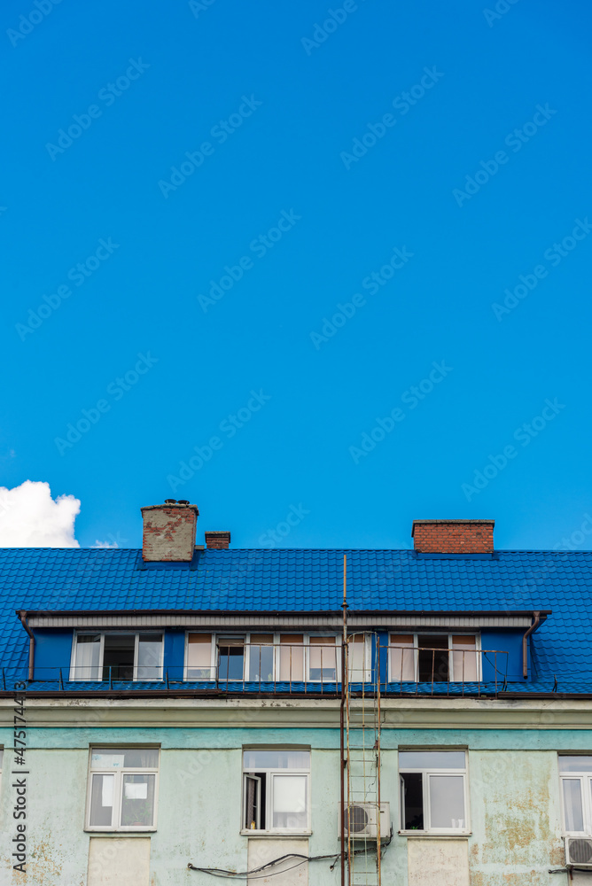 The top of the old facade with a roof on a clear sky background. The top of the old facade with a roof on a clear sky background.