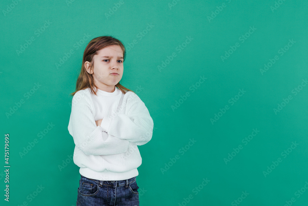 a boy with long hair with an aggrieved expression on a green isolated background. childish sadness