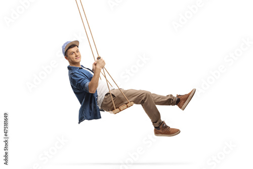 Side shot of a casual guy swinging on a wooden swing photo