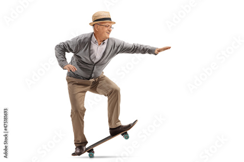 Full length profile shot of an elderly man performing a trick on a skateboard photo