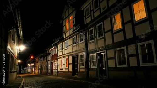 romantische gepflasterte Stra  e im n  chtlichen Goslar mit Fachwerkh  usern und beleuchteten Fenstern