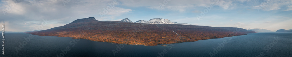 Panorama landscape with lake and mountains in Stora Sjöfallet National Park in autumn in Lapland in Sweden from above with clouds in sky.