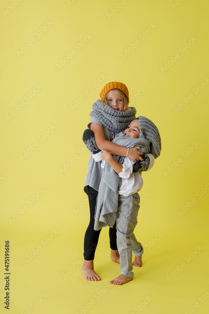 Adorable kids in knitted hats hugging in studio Adorable kids in knitted hats hugging in studio