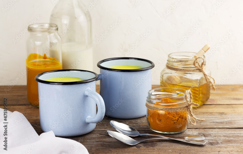 Two cups of golden milk, turmeric beverage and ingredients Two cups of golden milk, turmeric beverage and ingredients