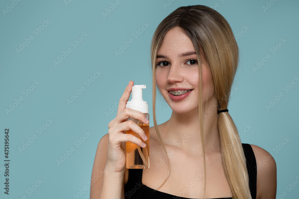 Young woman holds a bowl with a soap system. Turquoise background