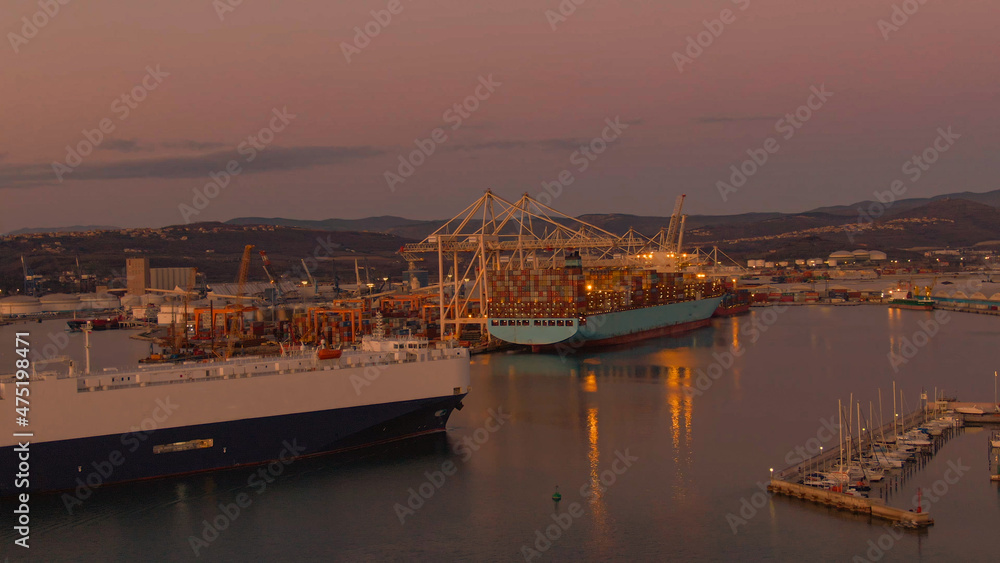AERIAL: Big Nautical lines carrier approaches the busy port of Koper at dusk.