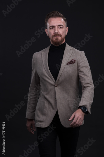 Confident businessman walking forward wearing a causal suit, handsome senior business man hero shot portrait isolated on black