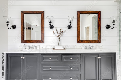 A luxurious renovated bathroom with a grey vanity, rustic wood framed mirrors, and chrome faucets and hardware. photo