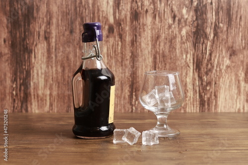 A bottle of liqueur and a glass with ice cubes