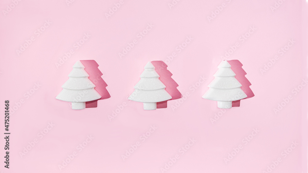 Three geometrical white Christmas trees on pastel pink background. Minimal romantic composition for Christmas or New Year's eve celebration or web banner Three geometrical white Christmas trees on pastel pink background. Minimal romantic composition for Christmas or New Year's eve celebration or web banner