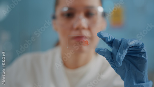 Woman biologist analyzing blood sample on glass tray to find diagnosis in laboratory. Researcher looking at dna molecule and substance for analysis and scientific development. Close up