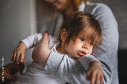 Small caucasian baby getting dressed mother young woman hold her child daughter girl while dressing her at home changing clothes real people family domestic life care and parenthood concept