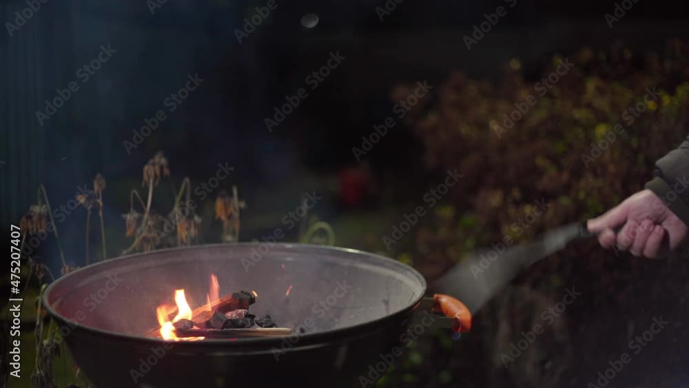 Red and hot coals shimmer beautifully in the dark. BBQ maker. Suburban leisure. Cooking dinner in nature. Natural firewood burns in the fire. Close-up of a hand fanning a fire Red and hot coals shimmer beautifully in the dark. BBQ maker. Suburban leisure. Cooking dinner in nature. Natural firewood burns in the fire. Close-up of a hand fanning a fire