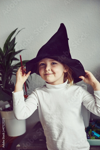 Naughty and sly preschooler girl ready to cast a magic spell. Little girl playing wizarding world at home