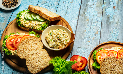 Homemade egg salad sandwich with wholewheat bun,cucumber, tomatoes,lettuce,egg,and cream cheese.  Rustic style. Selective Focus. Top view. Copy space. No.13