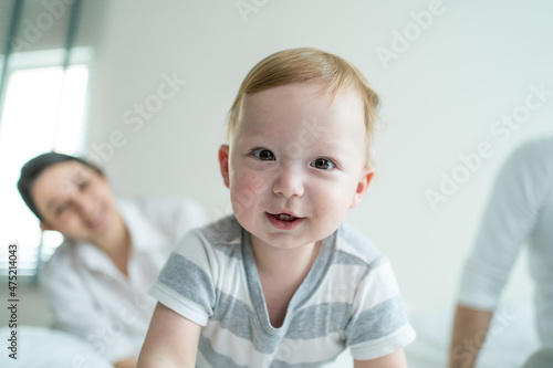 Caucasian parents playing with cute baby boy child on bed in bedroom. 