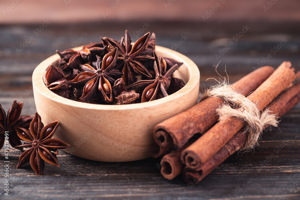 Star anise in bowl and cinnamon stick on wooden background Star anise in bowl and cinnamon stick on wooden background