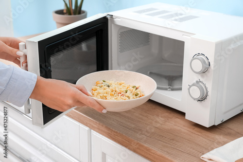 Woman heating food in microwave oven