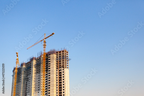Construction of a residential building. Construction cranes and house.