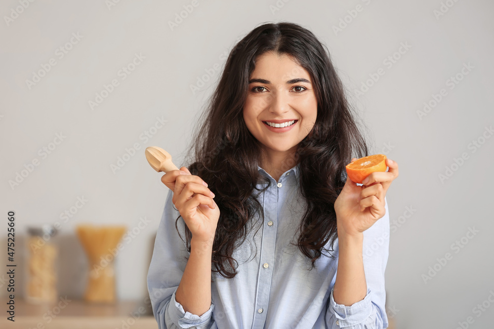 Young woman making fresh citrus juice in kitchen Young woman making fresh citrus juice in kitchen