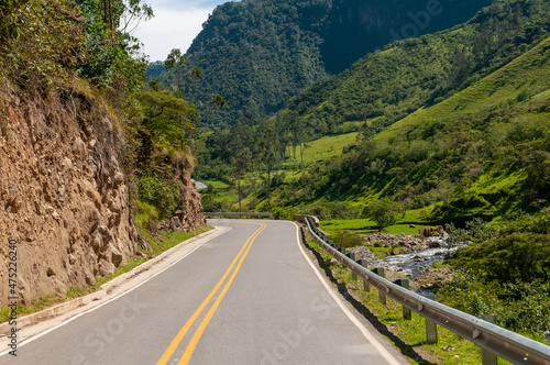 Road between tree-filled mountains and a river at the edge in a Colombian landscape.