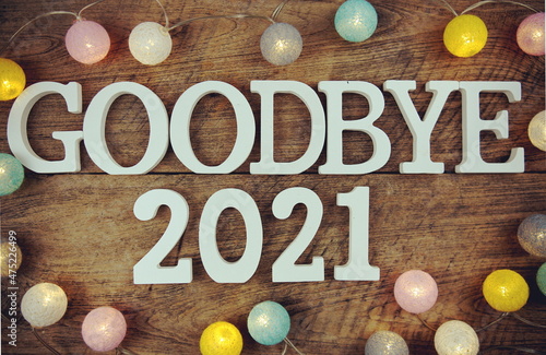 Goodbye 2021 alphabet letters and LED cotton ball decoration on wooden background