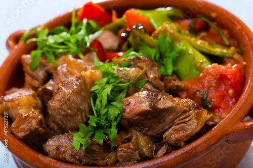 Portrait of cooked gyuvech dish of bulgarian cuisine of beef with vegetables at clay pot ..