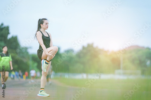 A mature beautiful Asian woman in sports outfits stretching before workout outdoor in the city stadium park in the morning to get a healthy lifestyle. Healthy young woman warming up outdoors