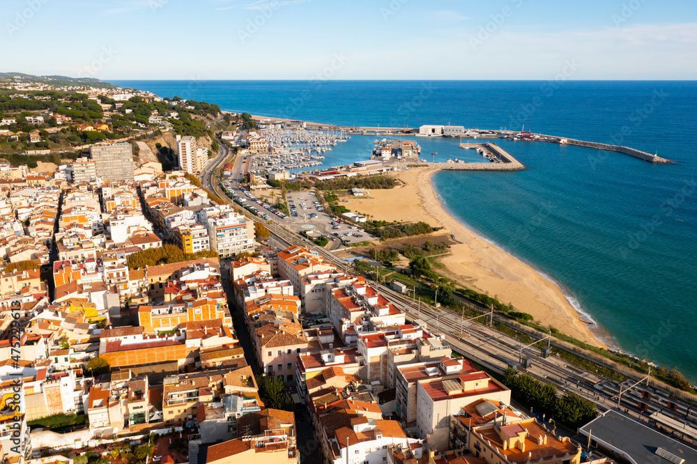 Picturesque drone view of coastal Spanish town of Arenys de Mar on bank of Mediterranean coast overlooking large sandy beach on sunny autumn day, Barcelona Province, Catalonia