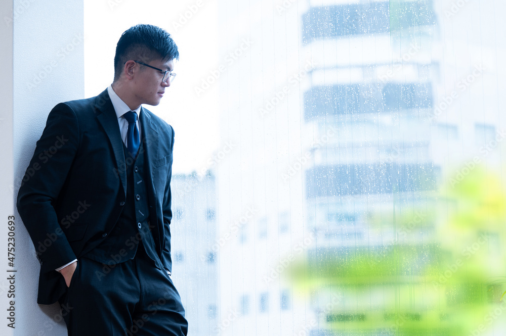 건물의 창가에서 내려다 보이는 아시아계의 잘 생긴 사업가 건물의 창가에서 내려다 보이는 아시아계의 잘 생긴 사업가